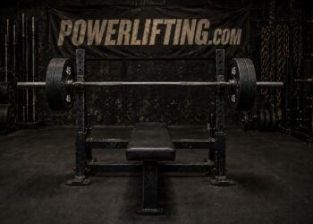 Powerlifting bench press setup with a loaded Olympic barbell on a flat bench inside a strength training gym, showcasing heavy weightlifting equipment for bench press training, powerlifting workouts, upper body strength, and competition preparation.