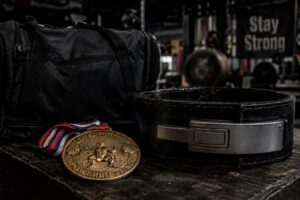 Powerlifting belt, competition medal, and gym bag displayed in a strength training gym, symbolizing dedication, achievement, and long-term success in powerlifting.