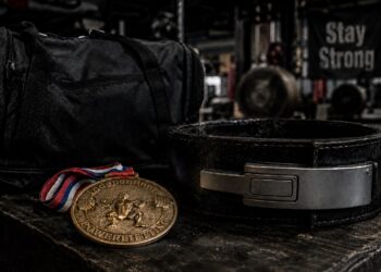 Powerlifting belt, competition medal, and gym bag displayed in a strength training gym, symbolizing dedication, achievement, and long-term success in powerlifting.