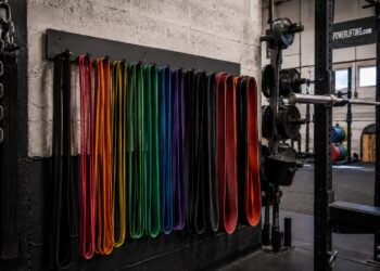 Resistance bands organized by color and tension level in a powerlifting gym, used for strength training, mobility exercises, and accommodating resistance.