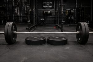 Loaded barbell set up for deficit deadlifts in a powerlifting gym, with weight plates used as a standing platform to increase range of motion, highlighting deficit deadlift training, posterior chain strength, pulling power, and powerlifting performance.