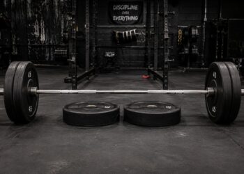 Loaded barbell set up for deficit deadlifts in a powerlifting gym, with weight plates used as a standing platform to increase range of motion, highlighting deficit deadlift training, posterior chain strength, pulling power, and powerlifting performance.