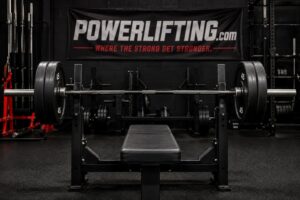 Bench press setup with a loaded barbell and flat bench, showing band instability techniques to enhance bench stability for powerlifting strength training.