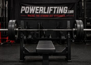 Bench press setup with a loaded barbell and flat bench, showing band instability techniques to enhance bench stability for powerlifting strength training.