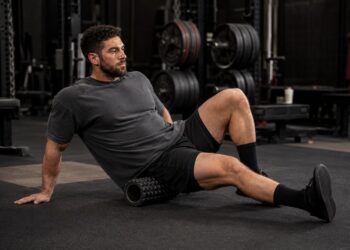 Powerlifter using a foam roller for hip recovery and mobility to support stronger squats and deadlifts in powerlifting.