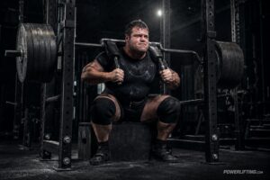 Powerlifter using the max effort method with a heavily loaded safety squat bar, strategic variation, and box squat training to avoid plateaus in powerlifting.